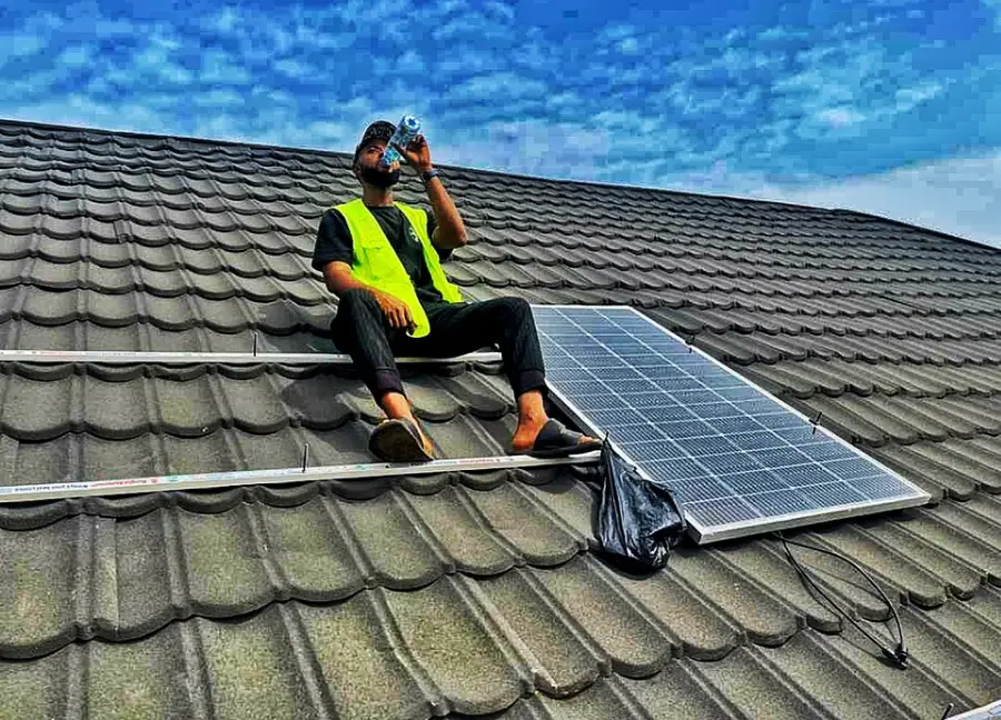 Nigerian solar technician installing rooftop panels